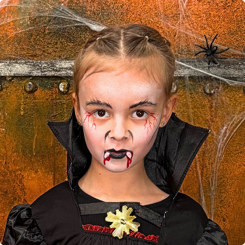 Child wearing a vampire face paint design from the Halloween kit